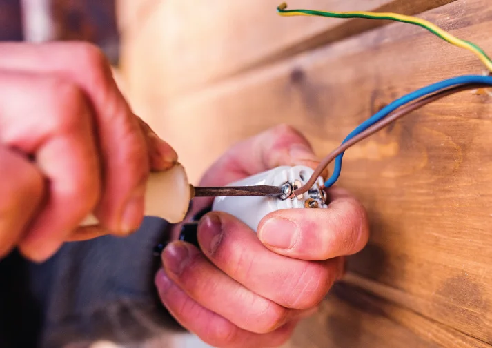 pair of electrician's hands working on installing small electrical equipment